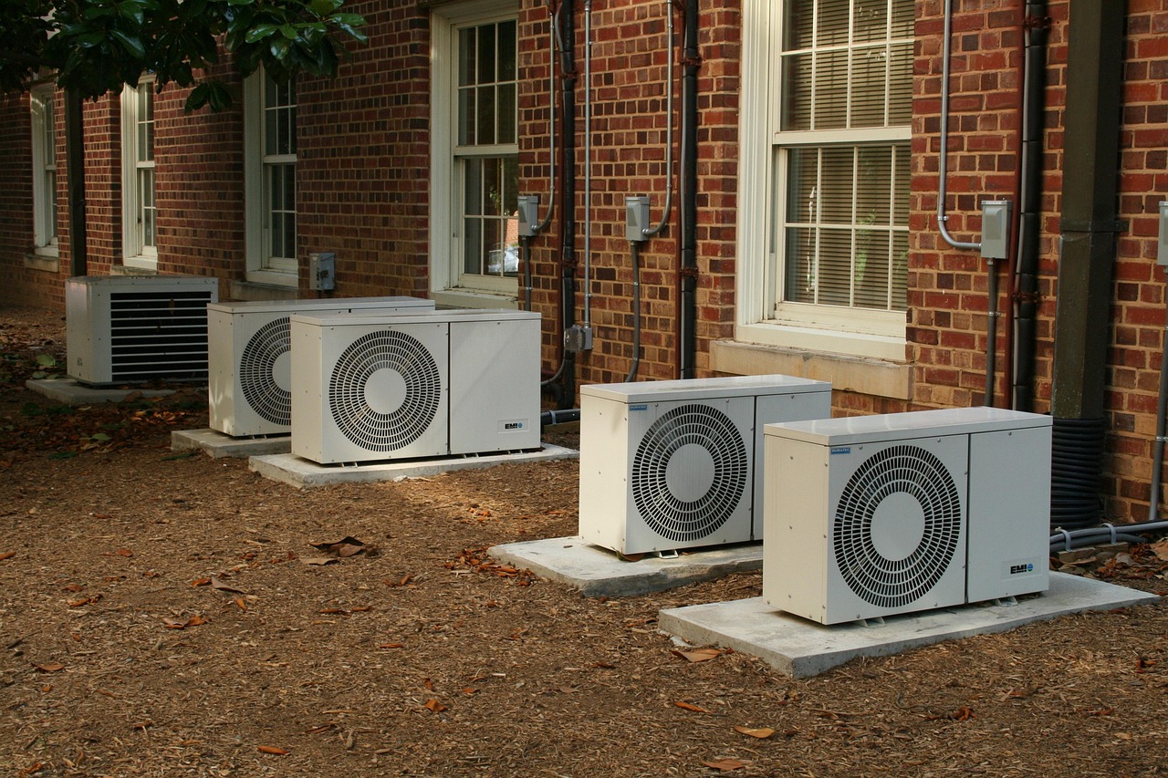 Row of outdoor AC condenser units mounted on a building exterior